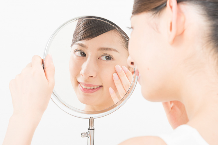 切らない眼瞼下垂手術後、鏡で仕上りを確認する女性